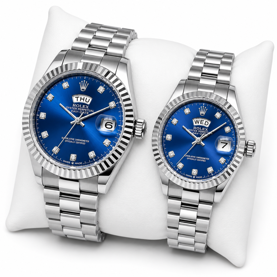 Two Rolex Datejust wristwatches with blue dial faces and stainless steel Oyster bracelets, displayed side by side on a white cushion. The larger watch on the left has a fluted bezel and a Thursday date, while the smaller watch on the right has a matching fluted bezel and a Wednesday date.