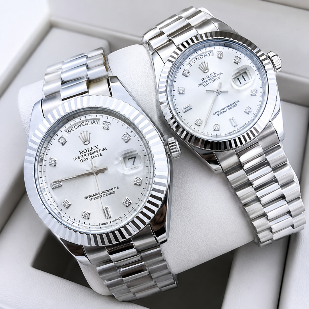 Two Rolex Oyster Perpetual Day Date wristwatches with silver stainless steel bracelets and white dial faces, displayed inside a white watch box.